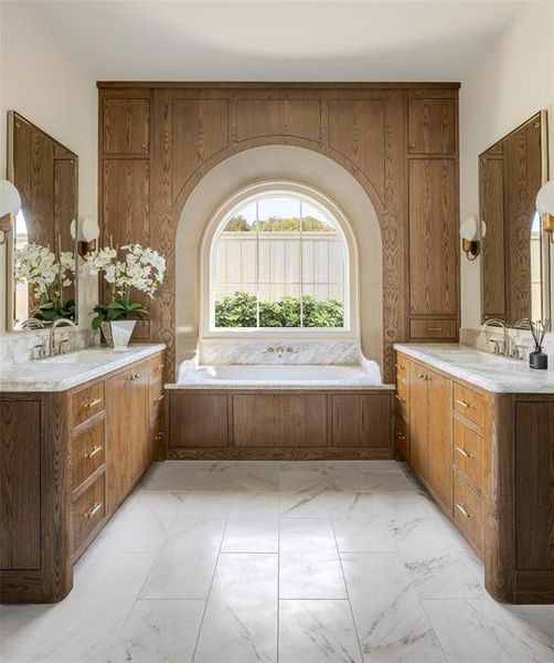 Full bathroom featuring a bath, two vanities, and light marble finish floors Full bathroom featuring a bath, two vanities, and light marble finish floors