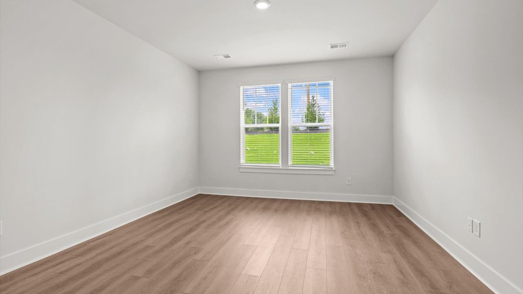 Elegant primary suite with hardwood flooring and superior natural light in this accomplished DRB Homes design