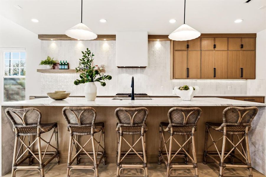 Kitchen with wood finish cabinets, a kitchen bar, backsplash, and light stone countertops