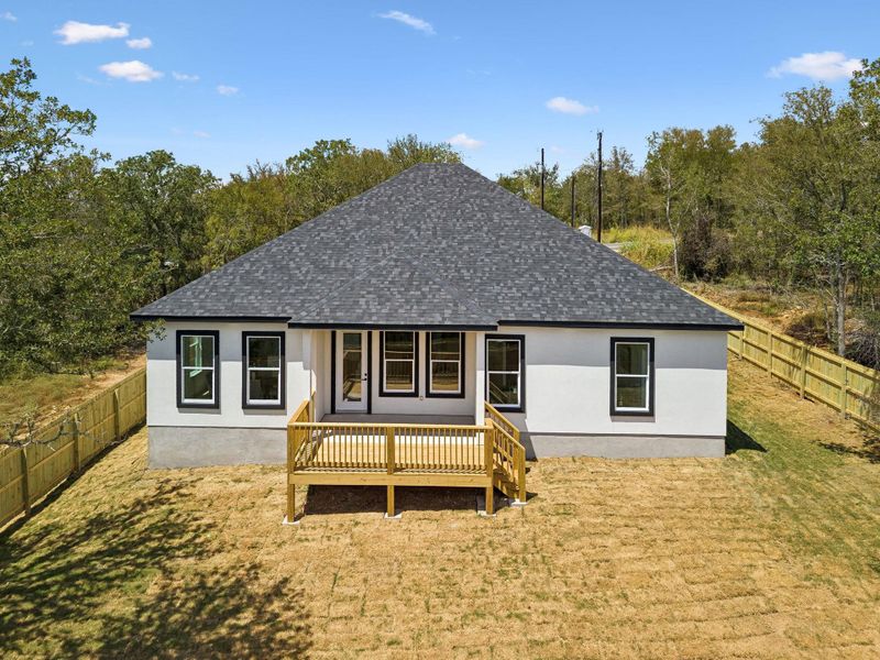 A spacious wooden deck overlooks the grassy backyard bordered by a privacy fence.