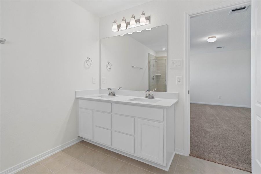 Wow! Look at this primary bathroom! Complete with cabinets and sleek light countertops, dual vanities, and large modern tile flooring. This bathroom is spectacular!