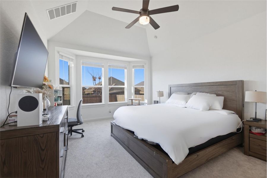 A spacious primary bedroom features bay windows, vaulted ceilings, and plush carpeting.