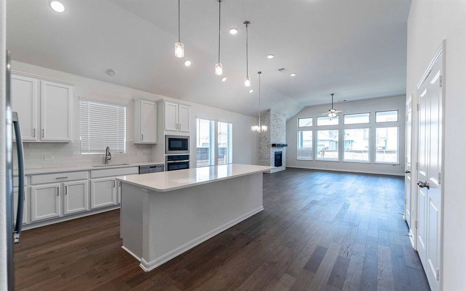 Open-concept living space featuring a gourmet kitchen with a central island, integrated stainless steel appliances, and quartz countertops