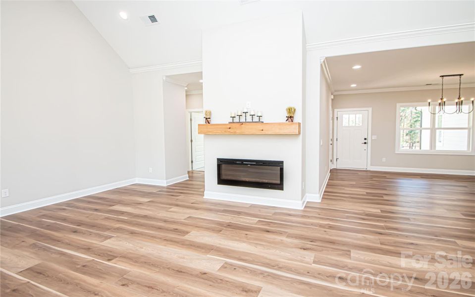 Bright, spacious family room with vaulted ceilings, recessed lighting, electric fireplace, and stylish LVP flooring throughout.