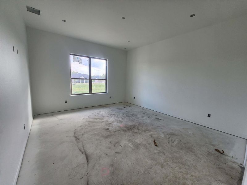 Spacious room featuring a large window, recessed lighting, and a concrete subfloor