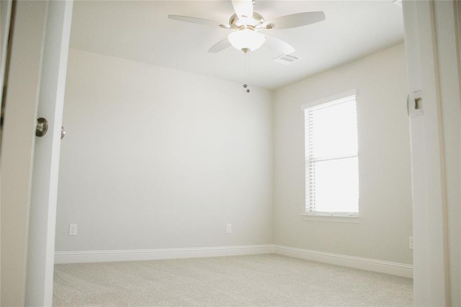 Carpeted spare room featuring ceiling fan