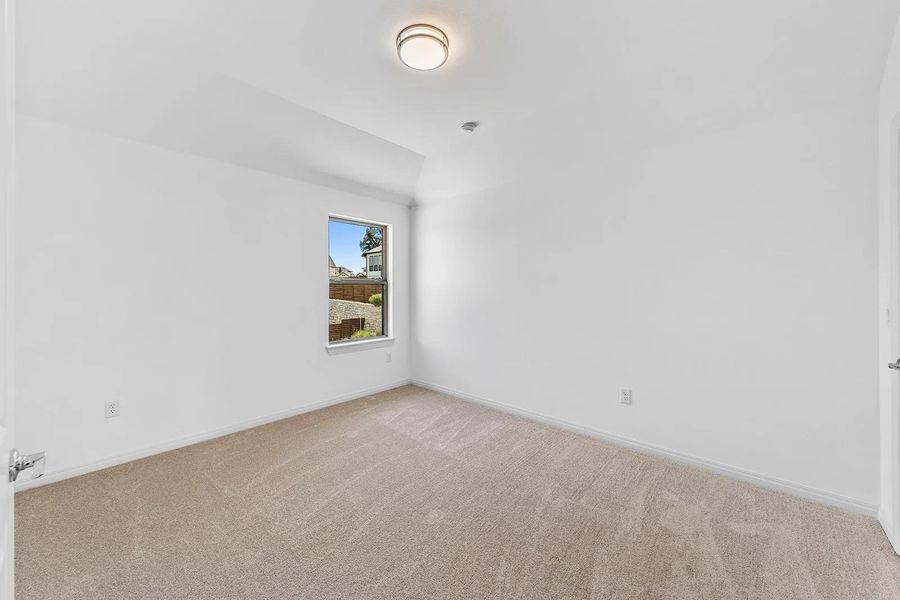 Unfurnished room featuring light carpet and vaulted ceiling