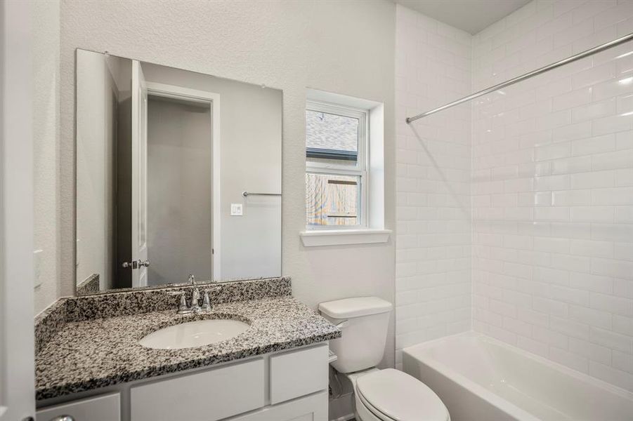 This ensuite bathroom is a space designed for both style and function with granite countertops and the crisp subway tiles in the shower/bathtub combo.