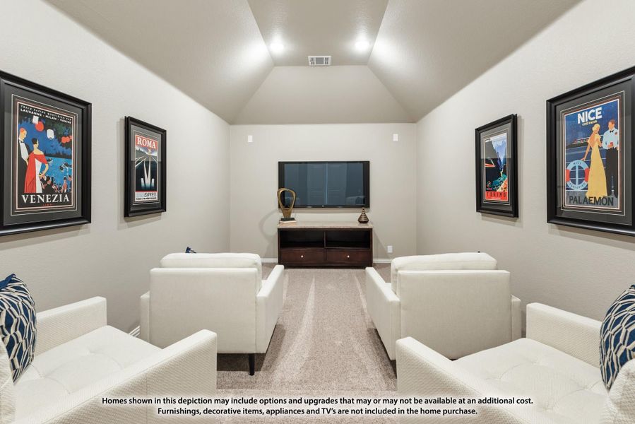 Media room with vaulted ceiling, wall-mounted TV, white chairs, and framed travel posters on both walls
