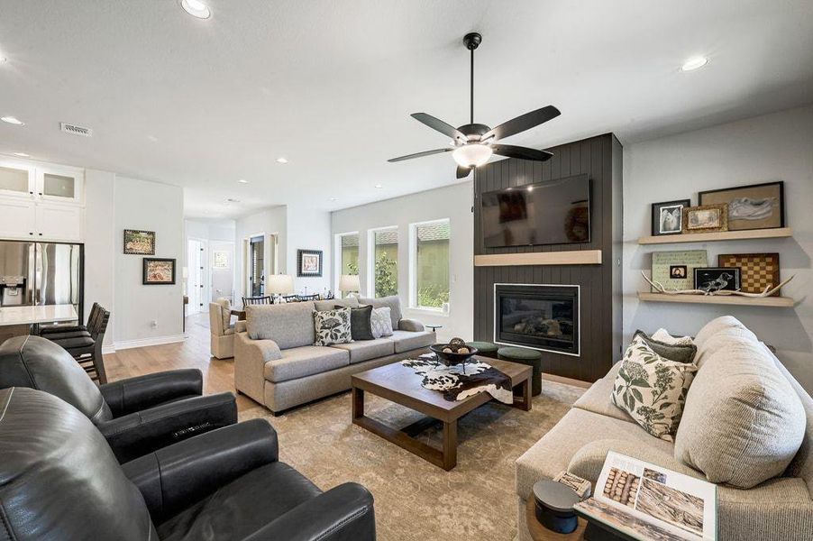 Living room featuring recessed lighting, a large fireplace, and light wood-type flooring Living room featuring recessed lighting, a large fireplace, and light wood-type flooring