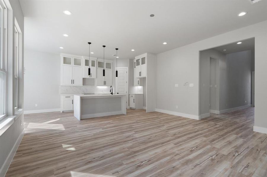 Kitchen with a center island, pendant lighting, white cabinets, and light hardwood / wood-style flooring