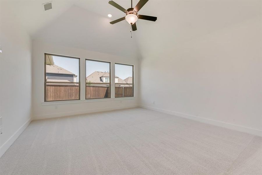 Empty room with light colored carpet, high vaulted ceiling, ceiling fan, and recessed lighting