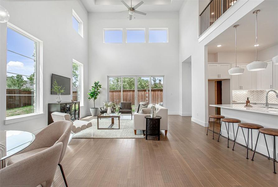 Living room with plenty of natural light, light wood-type flooring, and a high ceiling