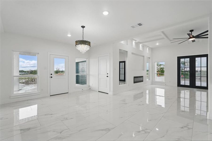 Unfurnished living room with healthy amount of natural light, a chandelier, light marble finish flooring, recessed lighting, and ceiling fan Unfurnished living room with healthy amount of natural light, a chandelier, light marble finish flooring, recessed lighting, and ceiling fan