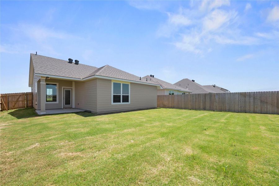 A vibrant green lawn extends from a comfortable patio area to a robust wooden privacy fence. A vibrant green lawn extends from a comfortable patio area to a robust wooden privacy fence.