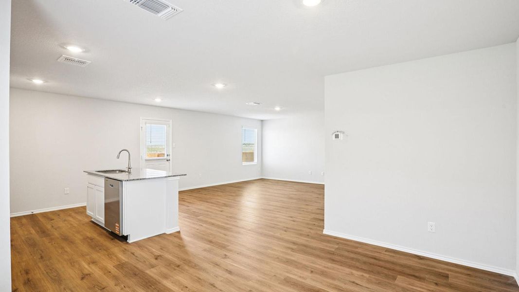 Open-concept living space with wood-finish flooring, recessed lighting, and white walls
