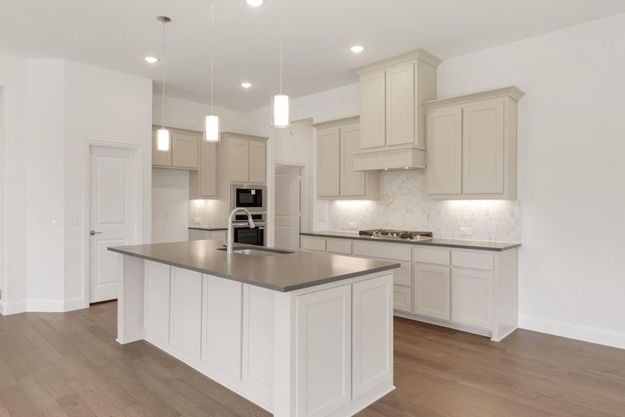 Kitchen with white cabinets, gray countertops, center island, pendant lights, and hardwood floors