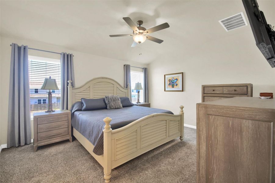 Primary bedroom featuring vaulted ceilings, neutral-toned walls, and carpet flooring
