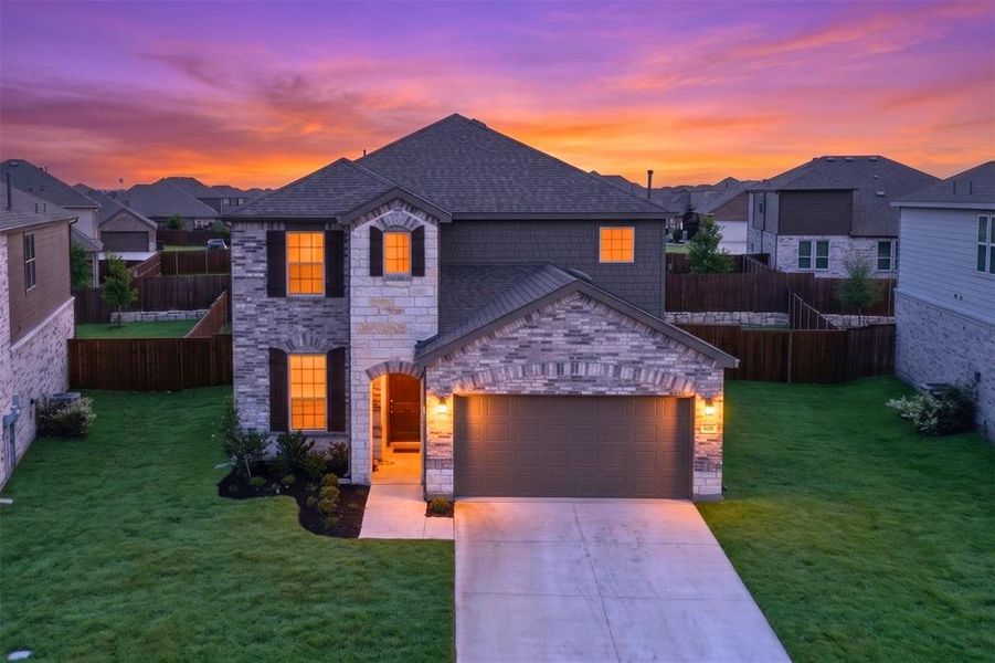 Two-story residence featuring a stone and brick façade, an attached two-car garage, and a concrete driveway