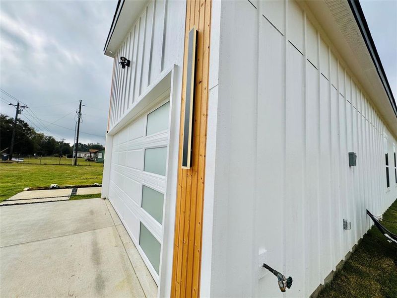 View of side of home featuring a garage, board and batten siding, and a yard View of side of home featuring a garage, board and batten siding, and a yard