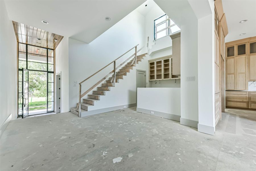 This picture was taken May 26th. This shows the entry and wet bar which features glass front cabinets, ice maker, beverage refrigerator and wrap around counterspace. The glass front cabinets and undercounter lighting will set the tone for this elegant space.