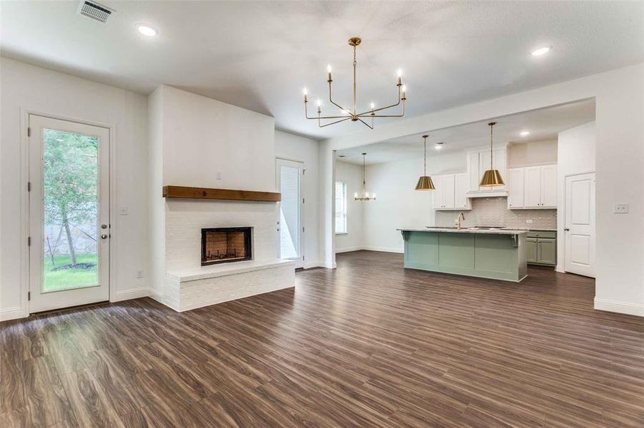 Unfurnished living room featuring a chandelier, baseboards, dark wood-style floors, recessed lighting, and a fireplace