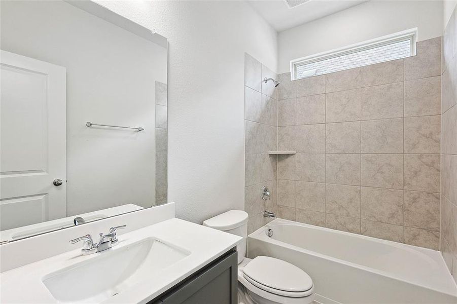 Full bathroom with tiled shower / bath, toilet, and large vanity