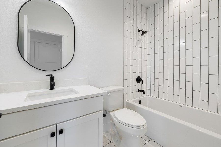 Bathroom featuring vanity, washtub / shower combination, and light tile patterned flooring