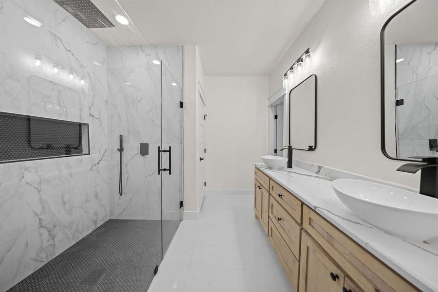 Bathroom with a marble finish shower, double vanity, and recessed lighting