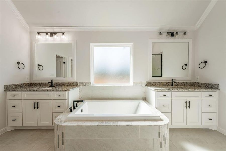 Bathroom with tiled bath, tile patterned floors, and vanity