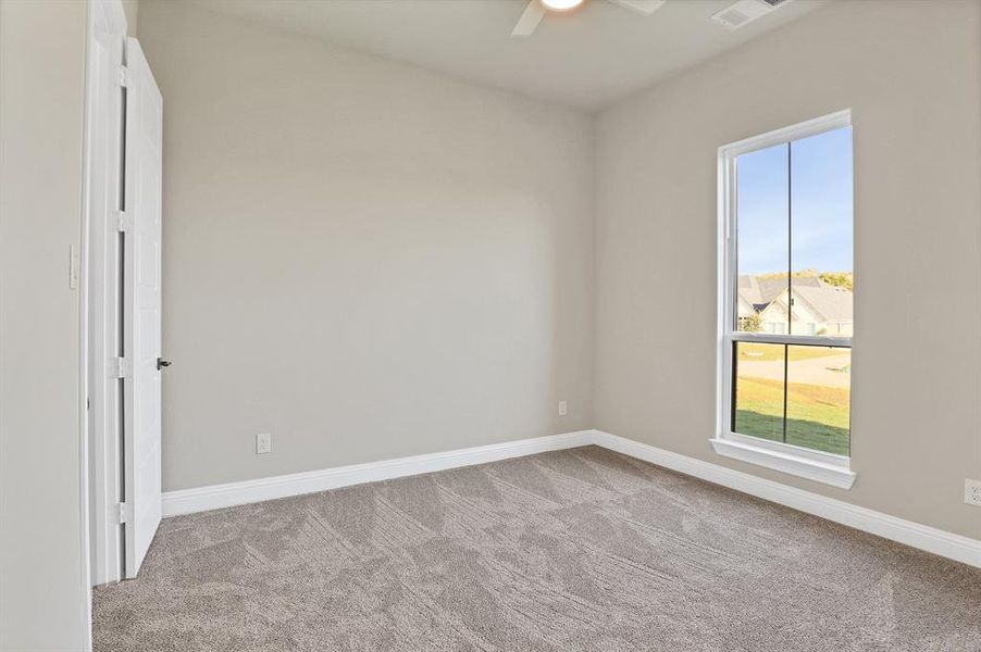 Unfurnished room with ceiling fan, a wealth of natural light, and light carpet