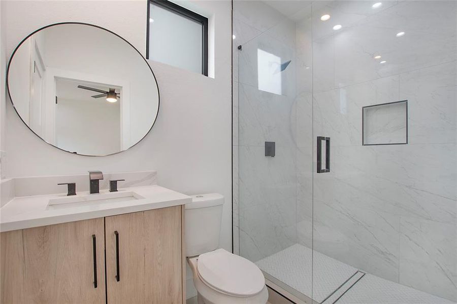 Bathroom with vanity, toilet, a shower with shower door, and ceiling fan