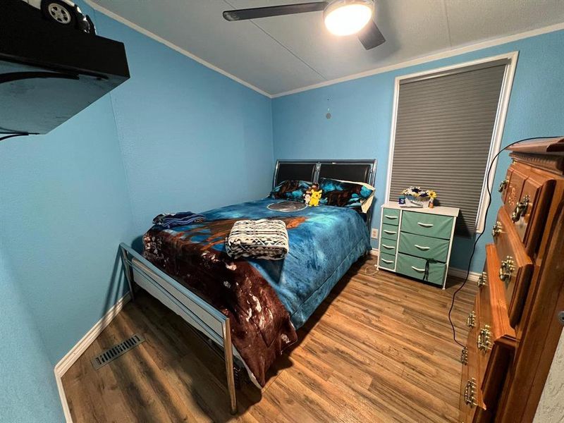 Bedroom with ceiling fan, wood-type flooring, and crown molding