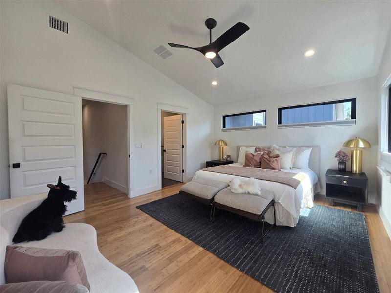 Vaulted ceilings and warm hardwood floors create an inviting atmosphere in this main bedroom.