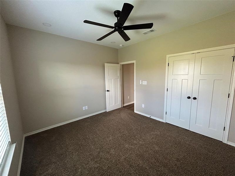 Unfurnished bedroom with carpet flooring, a closet, and a ceiling fan
