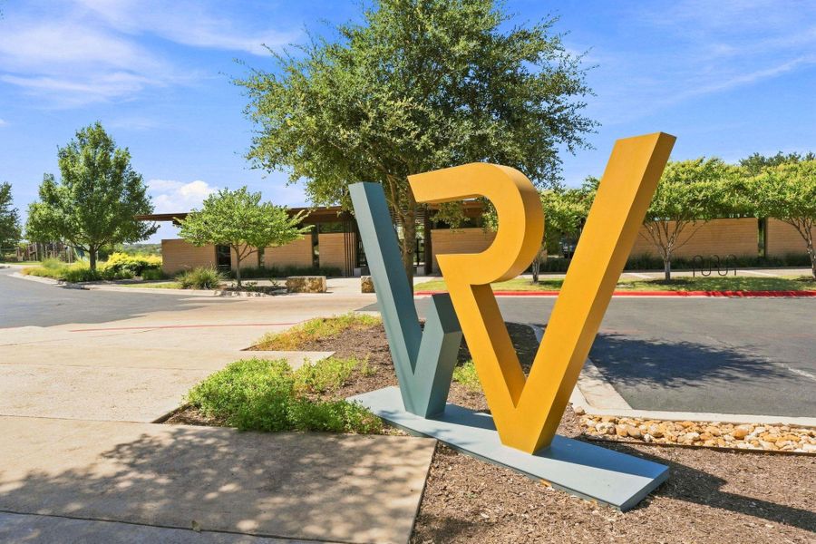 A welcoming entryway sign stands before the community clubhouse amidst manicured native landscaping.