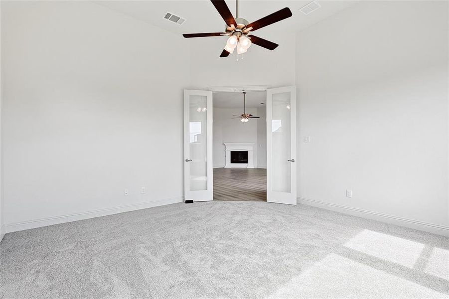 Carpeted spare room with a fireplace, a high ceiling, and ceiling fan