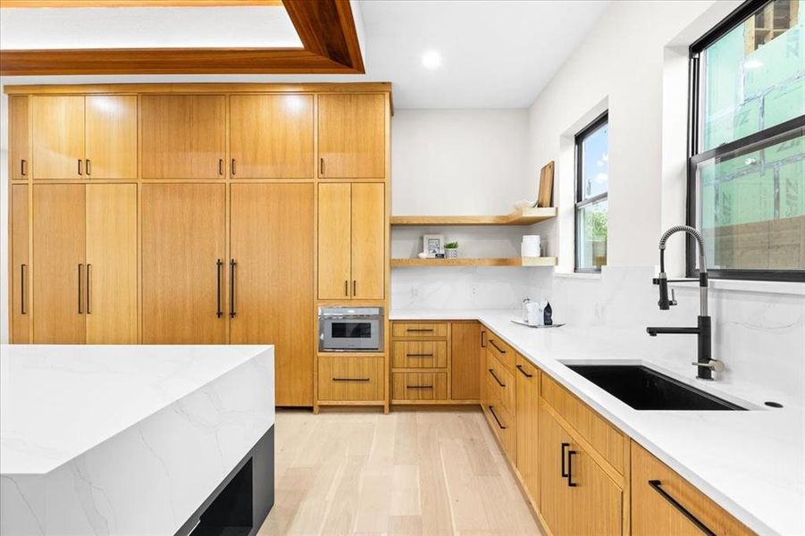 Kitchen featuring sink, light hardwood / wood-style flooring, tasteful backsplash, and light stone countertops