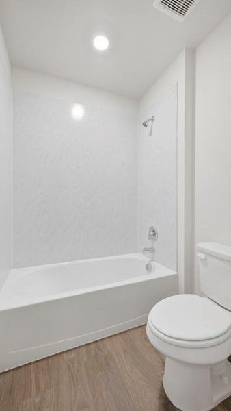 Bathroom with wood finished floors and washtub / shower combination