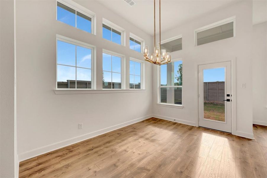 Open-concept room featuring high ceilings, wood-finish flooring, and ample natural light from multiple windows