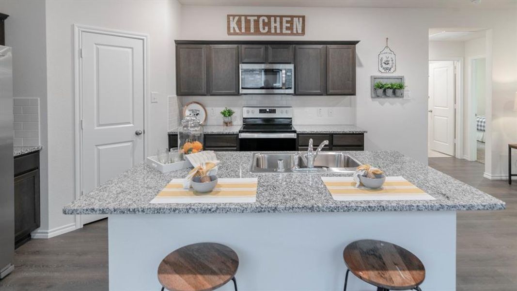 Kitchen featuring an expansive island with a double basin sink and granite-style countertop Kitchen featuring an expansive island with a double basin sink and granite-style countertop
