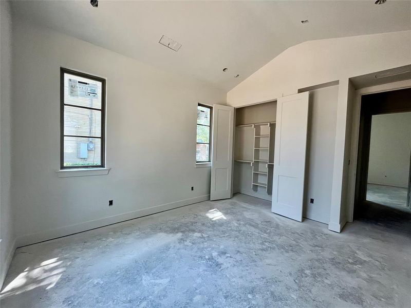 Unfurnished bedroom with vaulted ceiling and multiple windows