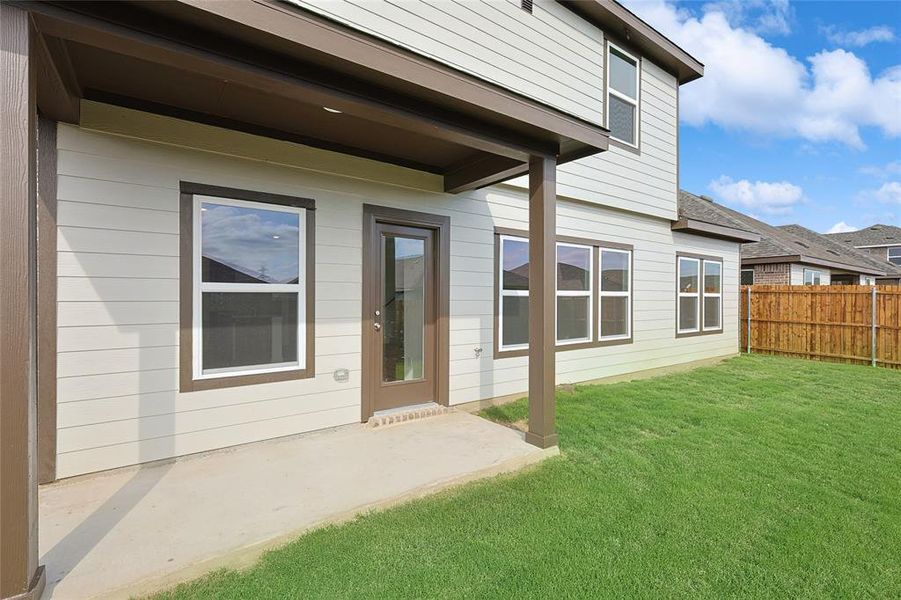 View of exterior entry with a patio area and a lawn