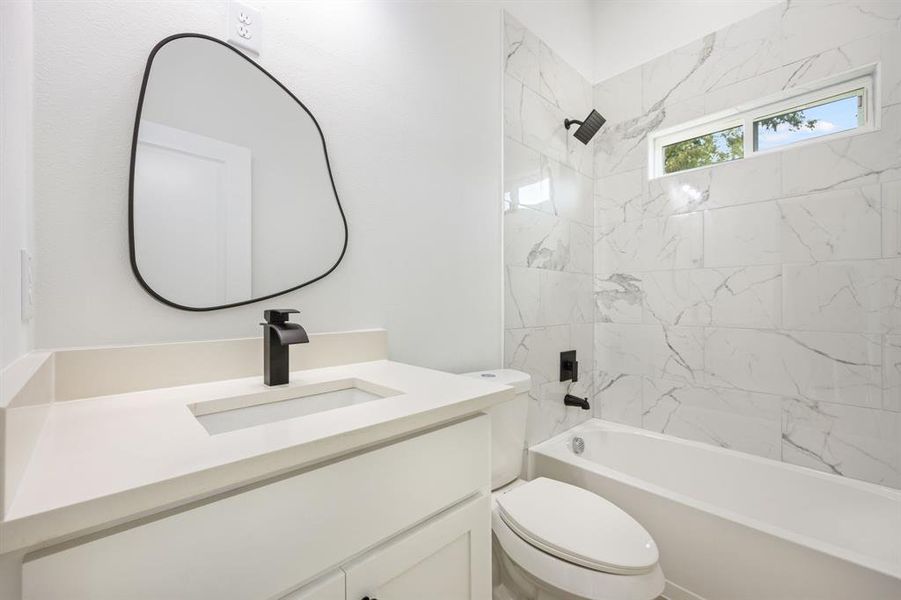 Full bathroom with vanity, tiled shower / bath, and toilet