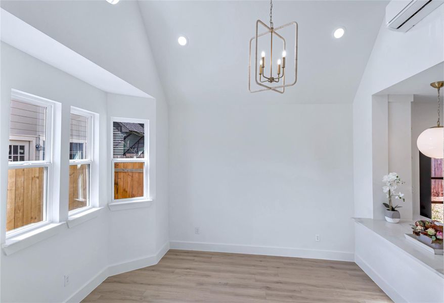 Dining space with recessed lighting, baseboards, vaulted ceiling, a wall mounted AC, and light wood-type flooring