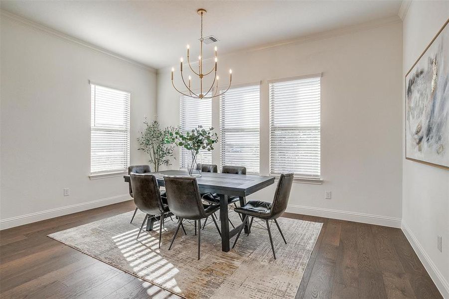 Dining space featuring chandelier, large windows to provide natural light, and crown molding