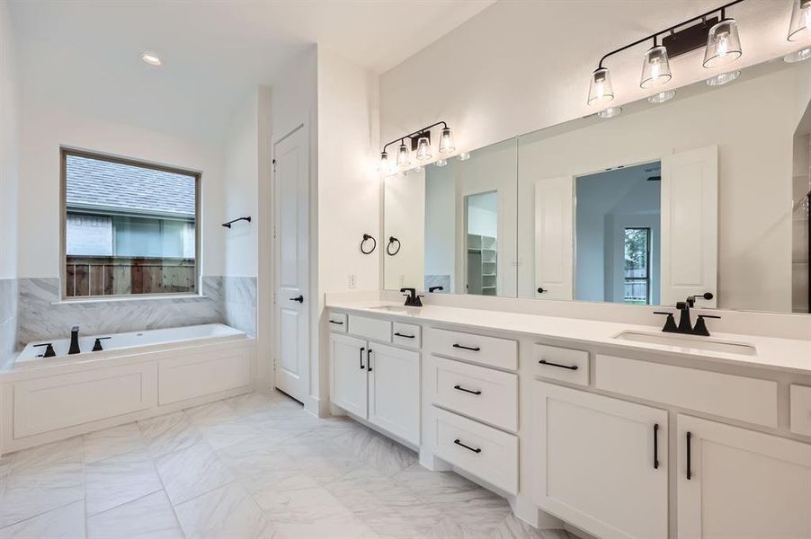 Bathroom with vanity, a bathing tub, and plenty of natural light