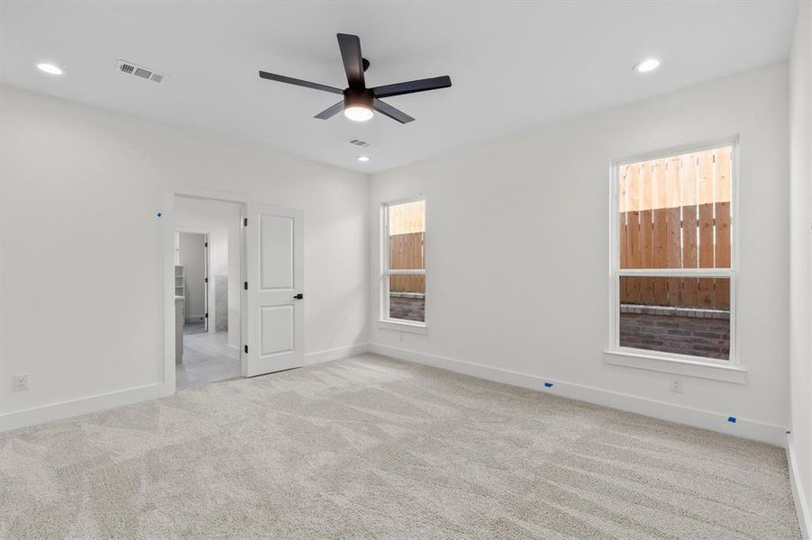 Unfurnished bedroom with ceiling fan and light colored carpet