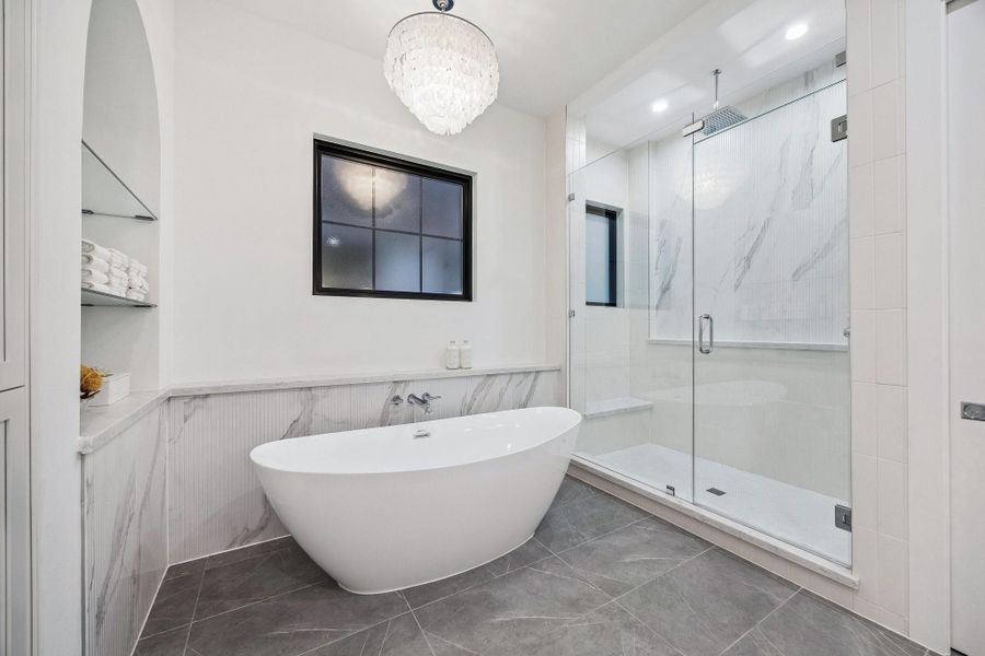Large Walk-in Shower with a Framless Shower Enclosure. The Floor in the shower is adorned with White Matt Penny Round 2 x 2 Mosaic Tile. The Shower walls are a mixture 3 x 12 Vertical Matt Tile and 16 x 48 Ribbed Urbanslat Marmi Grey Tile.