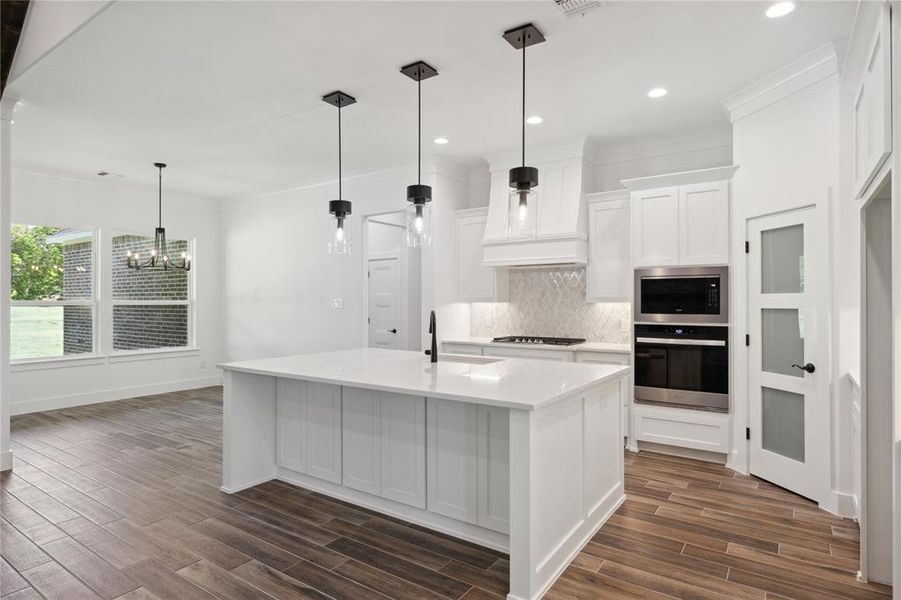 Kitchen with gas cooktop, a center island with sink, decorative backsplash, stainless steel oven, and built in microwave